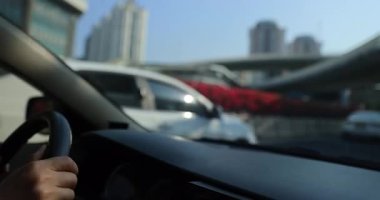 Şehir caddesinde binaları ve arka planda köprüsü olan bulanık bir trafik videosu var. Araba kullanan kişi. 