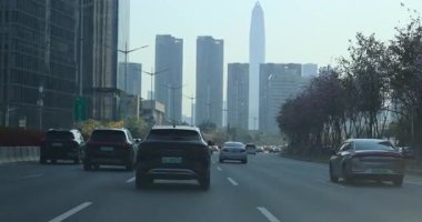Shenzhen şehrinin şehir merkezindeki şehir yolu, modern binaların yanından geçen arabalar. 