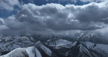 Çin 'de bulutlu bir gökyüzünün altında karla kaplı dağlar..
