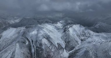 Çin 'de bulutlu bir gökyüzünün altında karla kaplı dağlar..
