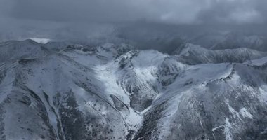 Çin 'de bulutlu bir gökyüzünün altında karla kaplı dağlar..