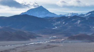 Issız ve düz bir arazide uzanan bir dağ sırası olan bir yolun videosu. Tibet, Çin