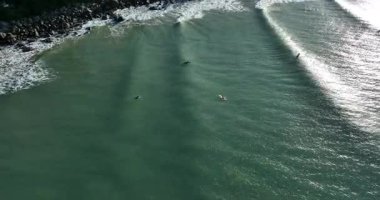 Okyanus dalgalarında sörf yapan insanların hava videosu..