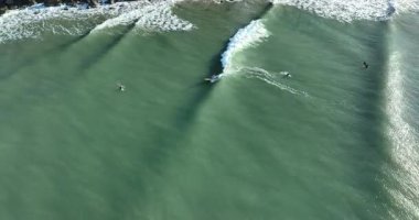 Okyanus dalgalarında sörf yapan insanların hava videosu..