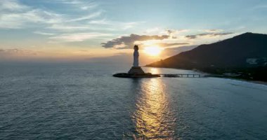 Gün batımında Çin açıklarındaki bir adada Guanyin 'in anıtsal heykelinin videosu. 