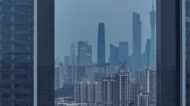 Geniş açılı bir video, gri ve bulutlu bir günde modern binalarla dolu yoğun bir şehir siluetini gösteriyor..