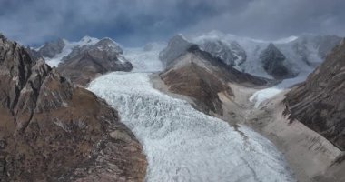 Geniş açılı bir video dağ vadisinden aşağı akan büyük bir buzulu gösteriyor..