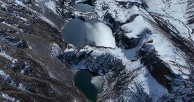 Karla kaplı dağ zirveleriyle çevrili el değmemiş dağlık göllerin havadan görünüşü