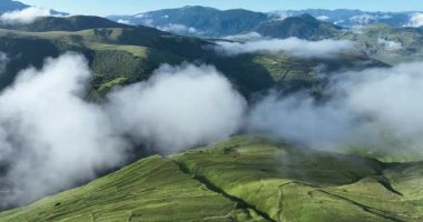Dağların manzarası ve bulutların uçuşunu gösteren hava aracı videosu. 