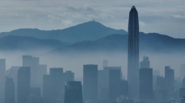 Havadan bakıldığında bulutlu havada gökdelenleri olan büyük ve modern bir şehir görülüyor. Çin 