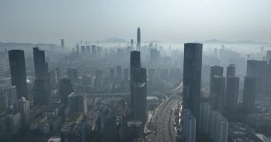 Havadan bakıldığında bulutlu havada gökdelenleri olan büyük ve modern bir şehir görülüyor. Çin 