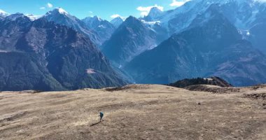 Uçsuz bucaksız bir arazide arka planda yükselen dağlarla yürüyüş yapan birinin videosu..