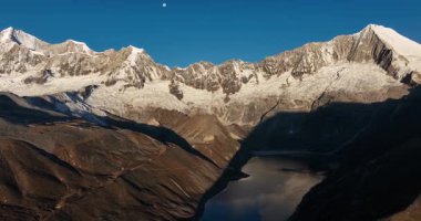 Devasa, karla kaplı bir dağ, gün doğumunda ya da batımında altın güneş ışığıyla parlar..