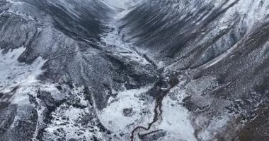 Bulutlu bir gökyüzünün altındaki karla kaplı sıradağların video görüntüleri..