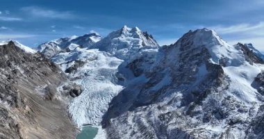 Muazzam karla kaplı dağlar, buzullar ve mavi gökyüzünün altında bir buzul gölü..