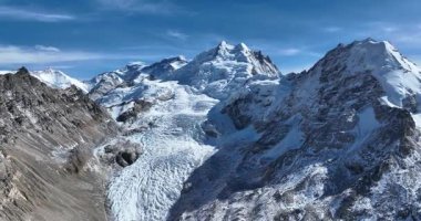 Muazzam karla kaplı dağlar, buzullar ve mavi gökyüzünün altında bir buzul gölü..