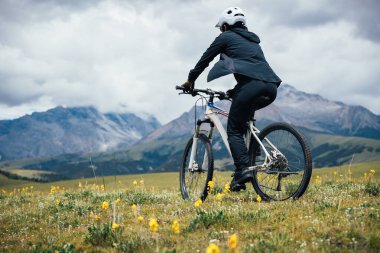Asfalt yolda görkemli dağlarda bisiklet süren sportif ve aktif bir motorcu. 