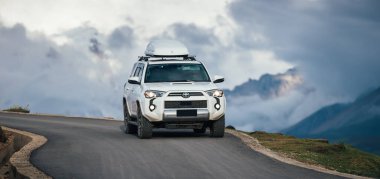 Dağlara ve mavi gökyüzüne park edilmiş modern bir araba.