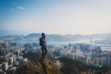Uçurumun kenarında durup Hong Kong 'da akıllı telefonuyla selfie çeken bir kadın.