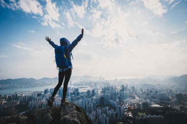Kadın yürüyüşçü uçurumun kenarında duruyor kollarını uzattı güzel Hong Kong 'a doğru.