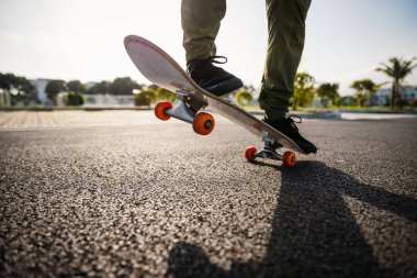 Kesilmiş görüntü. Otoparkta bir ayağı kaykayın üstünde duran ve sürmeye hazır biri.. 