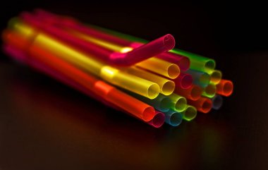 Masada birçok renkli plastik pipet aydınlatıldı. Kırmızı, yeşil, sarı, mavi, turuncu pipetler.