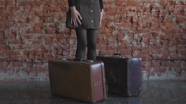 赤いレンガの背景に赤いレンガを背景にスーツケースを手にした少女 — ストック動画