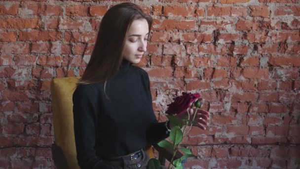 Joven Sentada Una Silla Con Una Rosa Roja Las Manos — Vídeo de stock