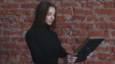 Elinde fotoğrafı olan genç bir kız.