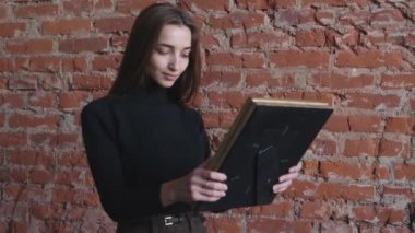 Elinde fotoğrafı olan genç bir kız.