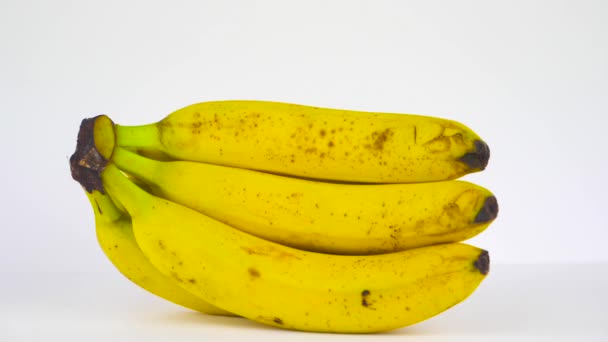 Желтые Бананы Белом Фоне Посыпанные Красными Листьями Роз — стоковое видео