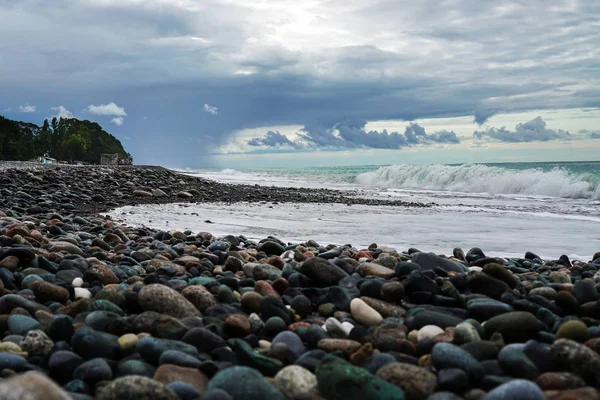 Karadeniz üzerinde çakıl plajı. Güzel bulutlar yağmur önce denize. Sörf dalgası. Abhazya. Gürcistan.