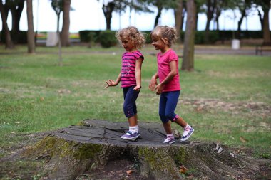 İki kız parkta eski güdük üzerinde duran