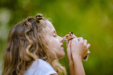 Hamster ile oynayan sevimli kıvırcık kız portresi