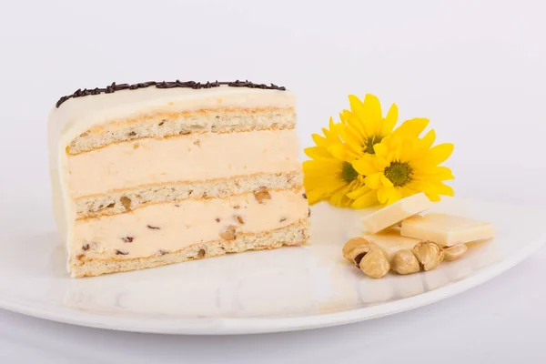 Piece of white cake on plate with yellow flowers and nuts