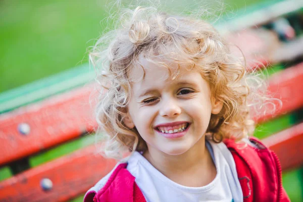 Ragazza Riccia Strizzando Occhio Seduta Sulla Panchina — Foto Stock