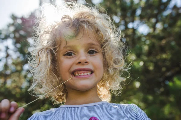 Portrait of smiling curly girl posing in summer garden