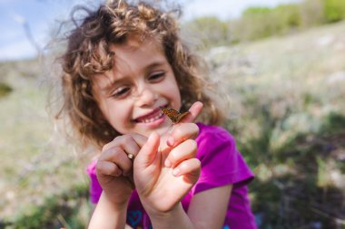 Kelebek üstünde parmak ile sevimli kıvırcık kız