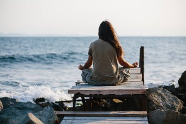 Deniz kenarında meditasyon uzun saçlı adam