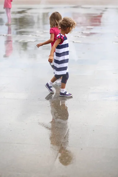 İki kızla birlikte oynayan asfalt yağmur sonrası ıslak.