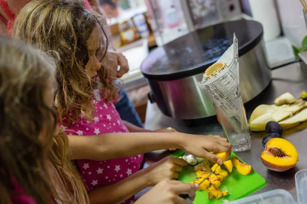 little girls making chimney cake in restaurant kitchen, with nonpareils and brown sugar