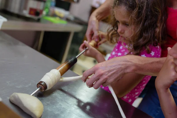 little girls making chimney cake in restaurant kitchen, with nonpareils and brown sugar