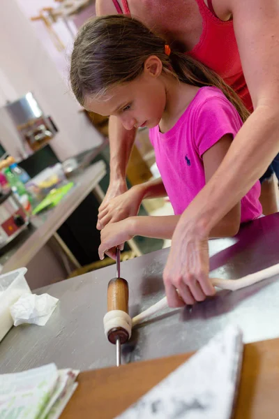 little girl making chimney cake in restaurant kitchen, with nonpareils and brown sugar