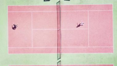 İnsanlar yazın kortta tenis oynuyorlar.