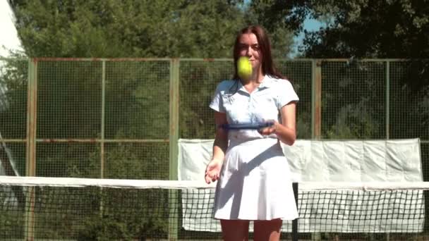 Ung idrottskvinna jonglerar tennisboll på racket — Stockvideo