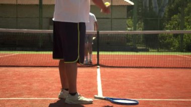 Kırpıcı adam rakipleriyle tenis maçına hazırlanıyor.