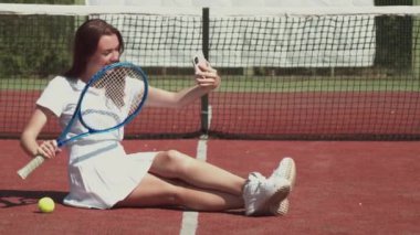 Neşeli sporcu kadın gülüyor ve raketle selfie çekiyor.