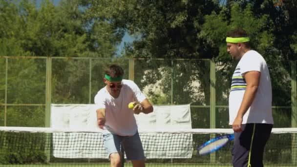 Esportista ensinando amigo masculino para jogar tênis — Vídeo de Stock