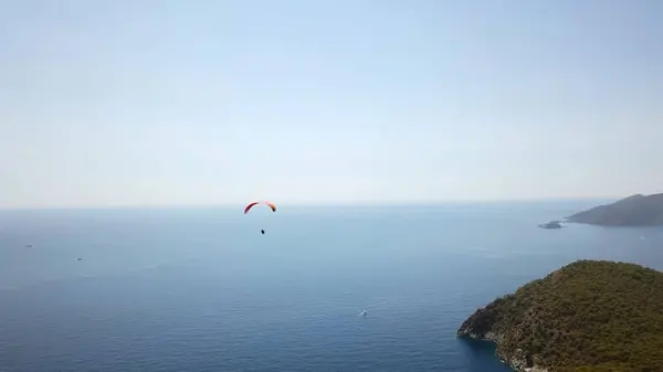 Paragliderler tatil köyünde deniz ve sahil üzerinde uçuyorlar.