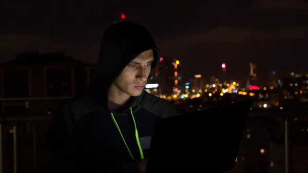 Hombre con capucha piratería sitio web por la noche —  Fotos de Stock